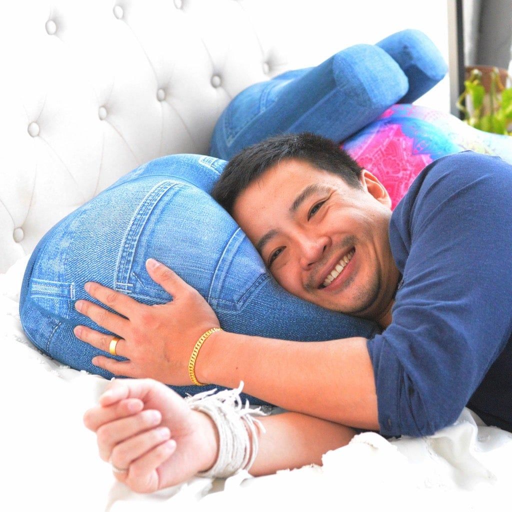 The Buttress Pillow OMG model in denim jeans cover - showing the ergonomic butt-shaped design that inspired our founder's vision